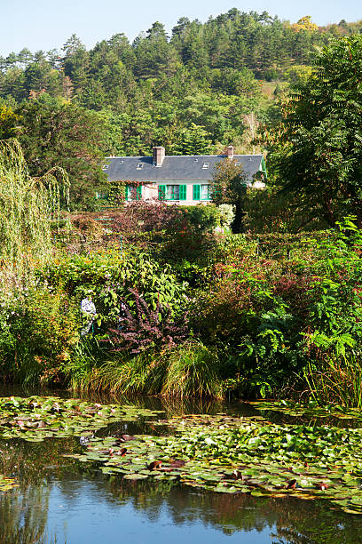 Monet's water lily pond in Giverny Monet's water lily pond made by Clode Monet himself - this scenery has been inspiration for a lot of his impressionistic artwork, His house painted in pink and green, his favourite colors, is seen in the background. claude monet photos stock pictures, royalty-free photos & images
