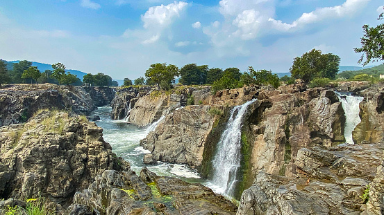 In the heart of a pristine wilderness, a spectacular waterfall tumbles gracefully over a rocky precipice, creating an awe-inspiring display of nature's power and beauty. The water, pure and clear as it descends, sparkles in the sunlight, resembling a cascade of liquid diamonds.