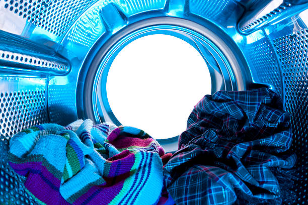 Laundry washing clothes rotating in machine drum front view. Household.