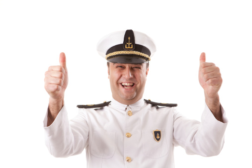 Happy little kid boy in sailor capitain hat and uniform playing with sailor boat ship. Smiling preschool child dreaming and having fun. Education, profession, dream concept.