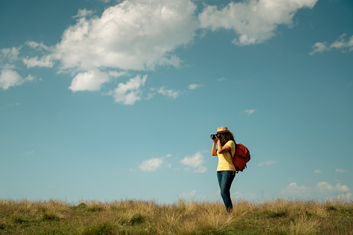 young female tourist takes photos in nature