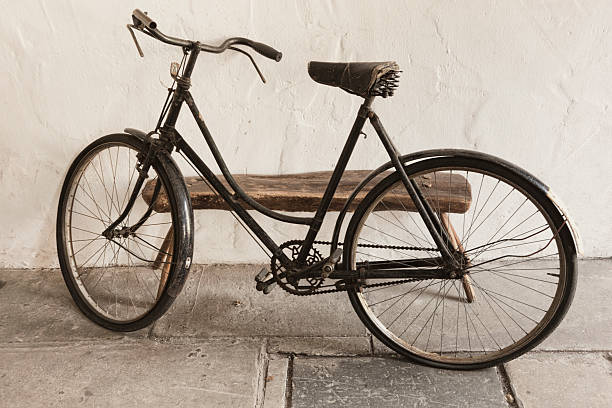 A very old and somewhat battered bicycle against a whitewashed stone wall.