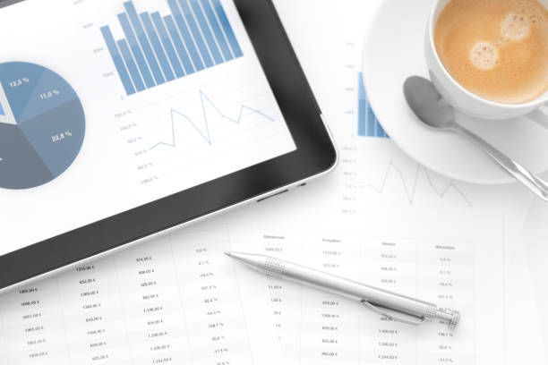 istock Tablet showing charts next to worksheets a pen and coffee 184988141