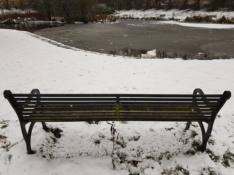 A park bench on a snowy day at a park in Glasgow Scotland England UK