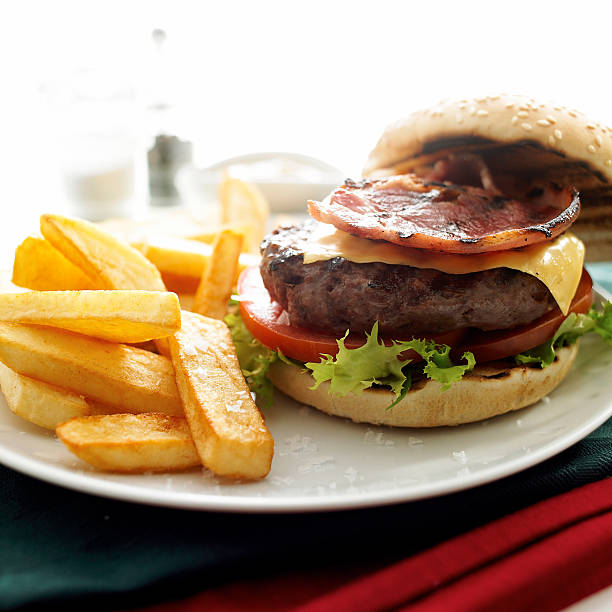 Tasty cheeseburger  on a plate with a bacon and side chips.