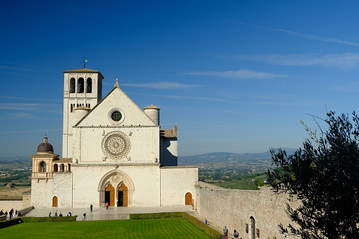 Assisi, Umbria, Italy. About october 2019.  Basilica of San Francesco with the lawn with green grass in front and the blue sky.