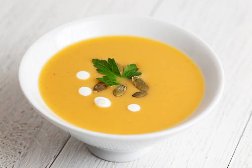 Bowl of squash soup topped with pumpkin seeds