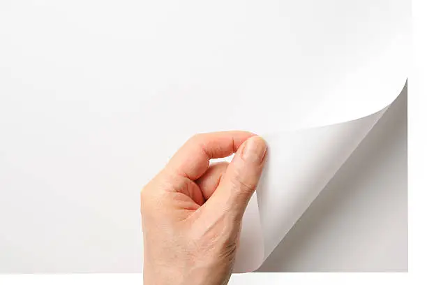 Close-up shot of a hand turning a blank page isolated on white background with clipping path.