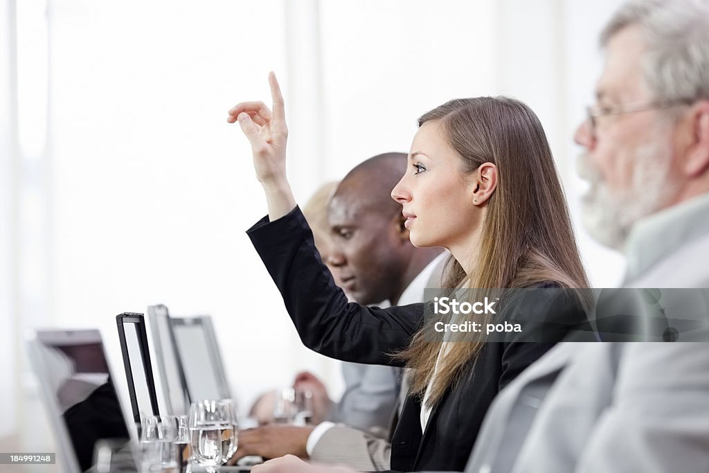 Empresaria elevar la mano en una reunión de negocios - Foto de stock de 25-29 años libre de derechos