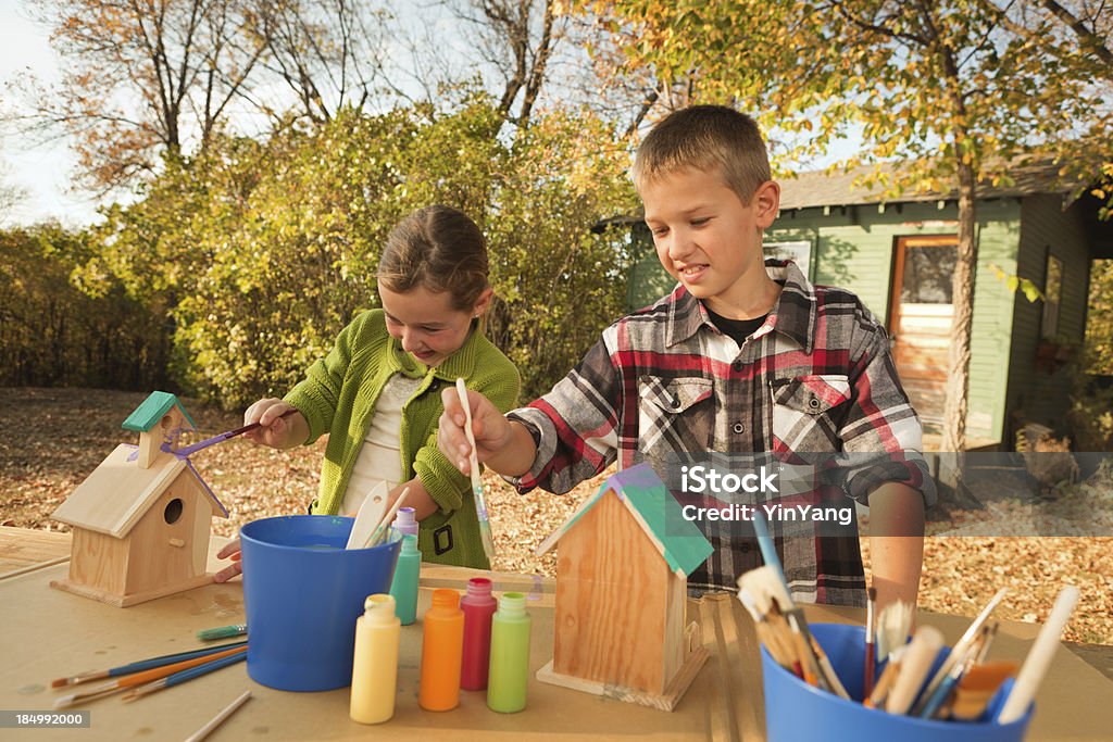 Children Working on Fun Project of Painting Birdhouse Hz "Subject: Children, brother and sister playing together working on painting birdhouses in the backyard of their home.Location: Midwest, USA." Birdhouse Stock Photo