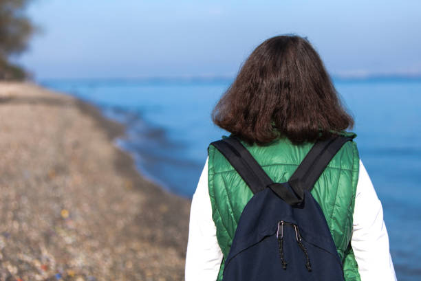Lonely woman with backpack walking by the sea