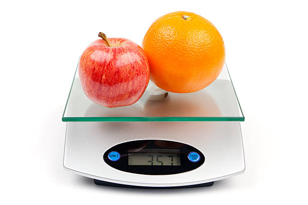 apple y naranja en escala - weight scale apple comparison balance fotografías e imágenes de stock