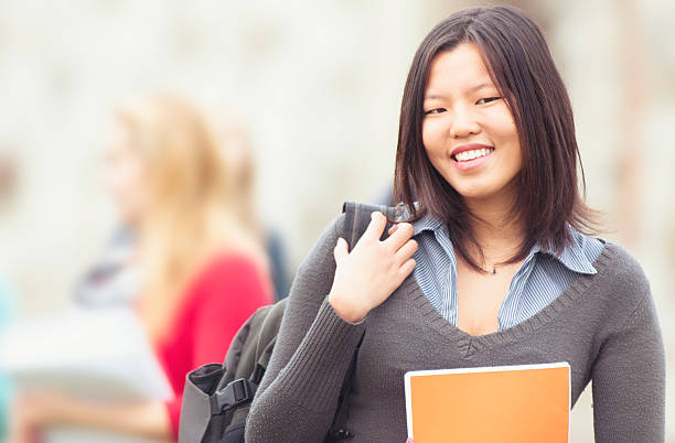 istock Asiatic female college student outdoors holding a book 184993020