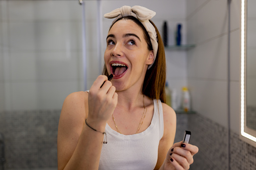 Caucasian woman accentuates her lips with precision while applying lipstick in bathroom