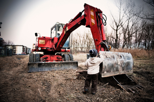 Child admiring a red excavator.