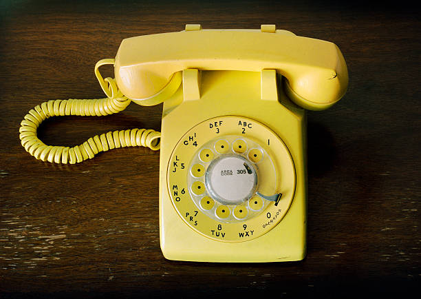 istock Old Fashioned Retro Yellow Rotary Phone on Wood Table 184993690