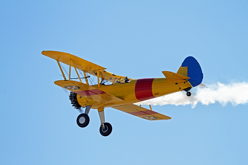 Vintage Stearman bi-plane in flight with smoke on.