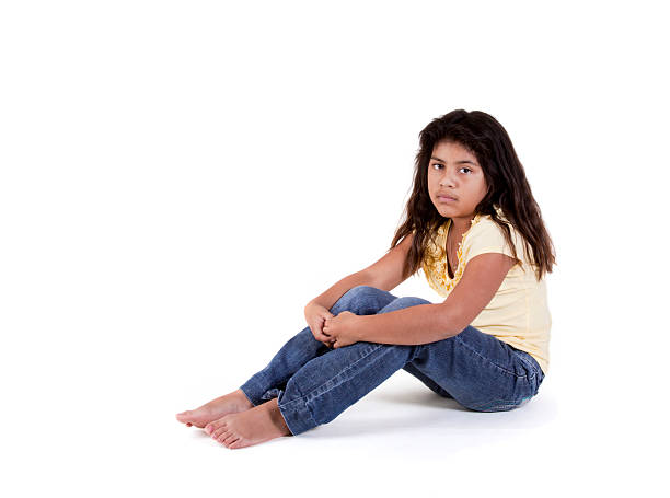 portrait of a sad looking preteen girl on black background