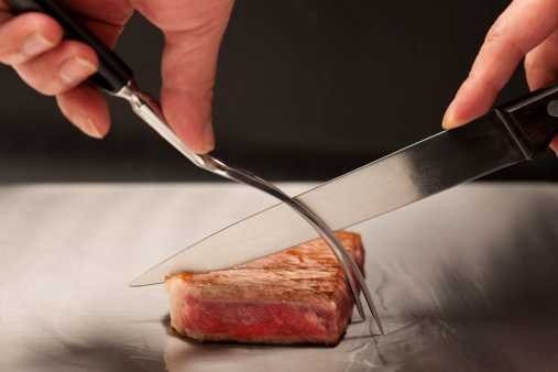 A chef cutting Sirloin steak on Teppanyaki table.