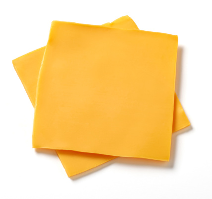 Two slices of processed American cheese on white background with natural shadow.