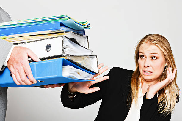 istock Young businesswoman tries to avoid huge stack of work files 184995568
