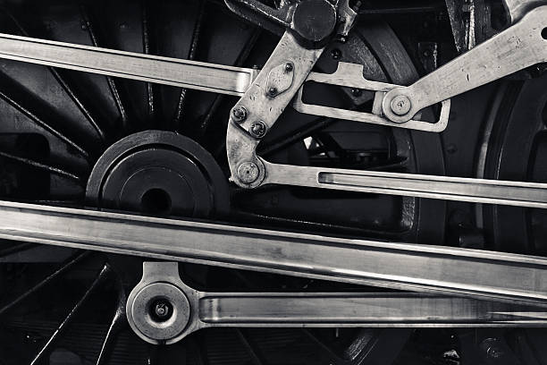 Close-up of steam locomotive driving mechanism, revealing intricate red and white wheels with connecting mechanical components