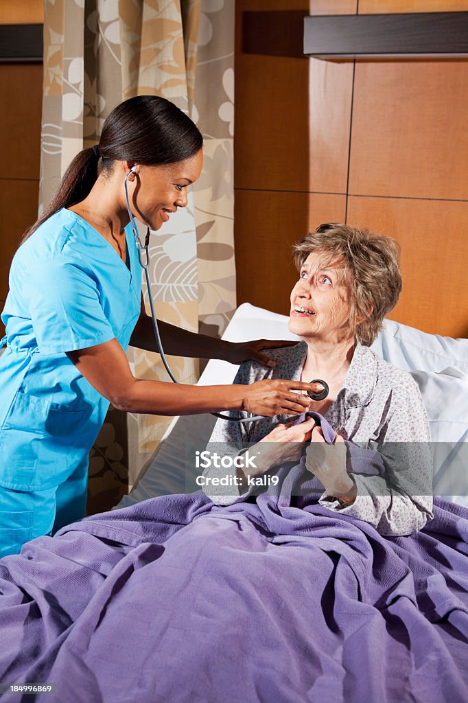 Medico o l'infermiere esaminando donna anziana in ospedale camera - Foto stock royalty-free di Convalescenza