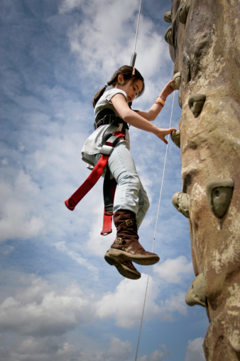 Eight-year-old girl descending from a rock wall climb.