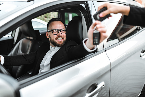 Male Driver Taking Car Keys From Businesswoman