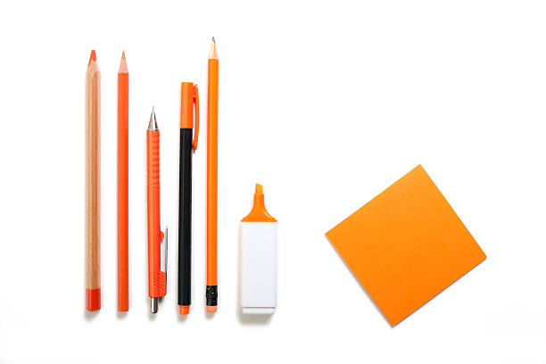 orange colored pen, pencil, highlighter and post it stock photo