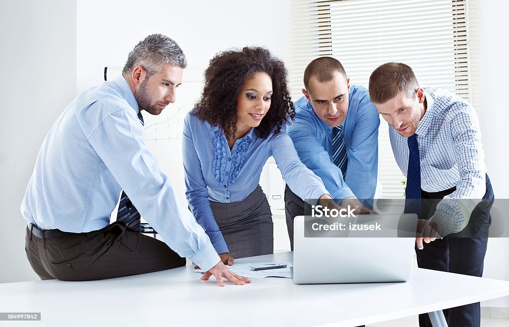 Discussing project Four business people discussing project on laptop in meeting room. Men Stock Photo