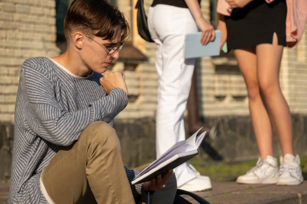 istock Male student with book sits on step near university 1849979794