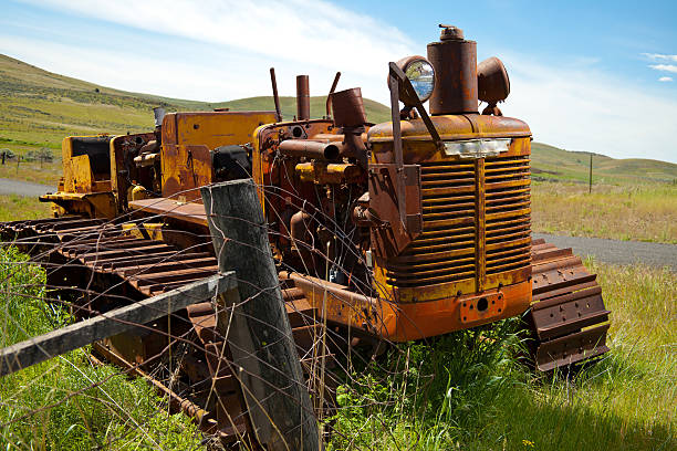 istock Old orange  tractor in a green field on the tracks 184998496
