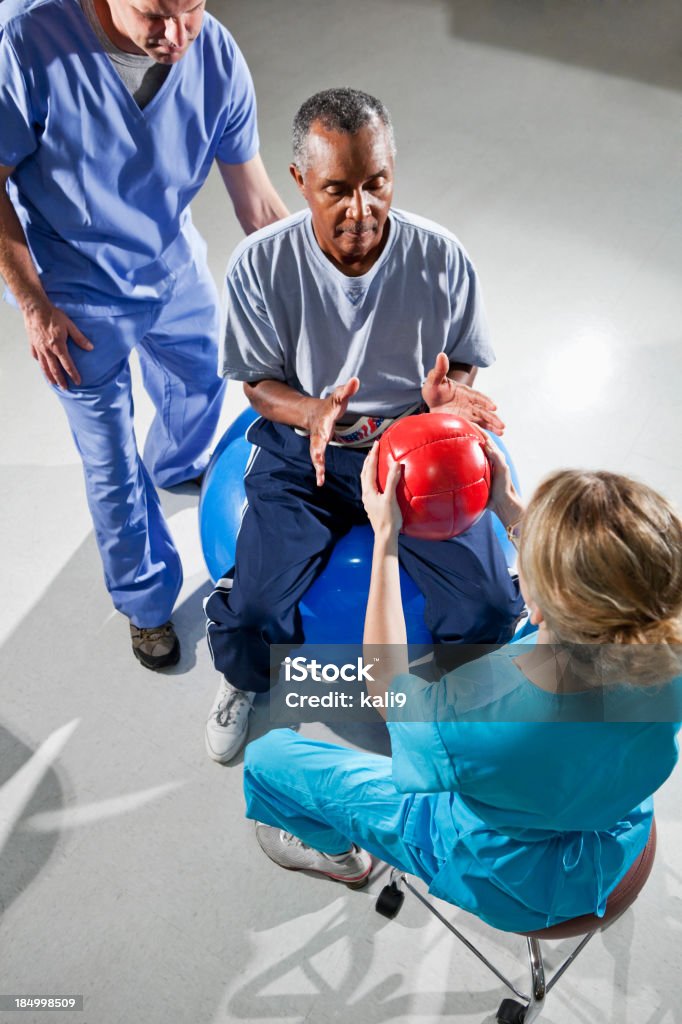 Homem sênior com físico terapeutas usando bolas de ginástica - Foto de stock de 30 Anos royalty-free