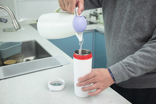 Close Up Photo Of man Hands Pouring  Tea From Teapot Into A Cup