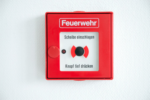 New Red Fire Alarm Box - Break Glass and push the Button. German fire alarm box with inscription Feuerwehr.