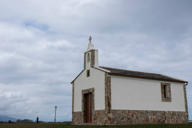 istock A small white chapel with a stone base under a cloudy sky, next to a grass field and a lamppost 1849988934