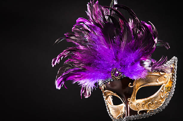 Golden masquerade carnival mask with purple feathers Ball mask. Golden masquerade carnival mask with purple feathers isolated on black background. purple and gold masquerade masks stock pictures, royalty-free photos & images
