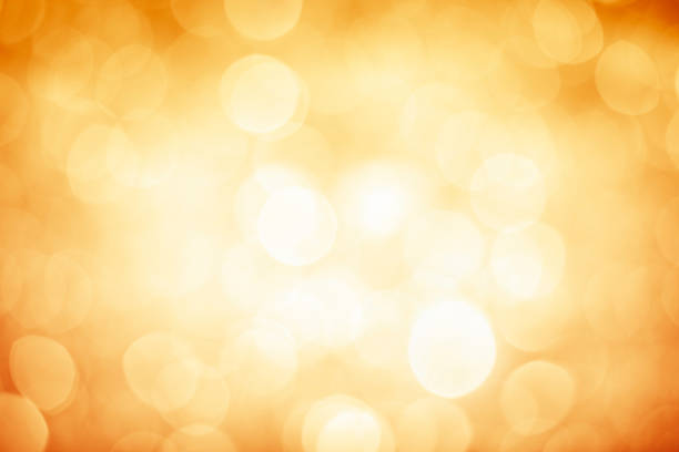 Blurred gold sparkles background with darker corners and bright center stock photo