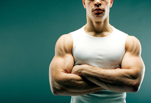 Strong guy with crossed arms Male person with strong arms in white shirt over green background. pectoral muscle stock pictures, royalty-free photos & images