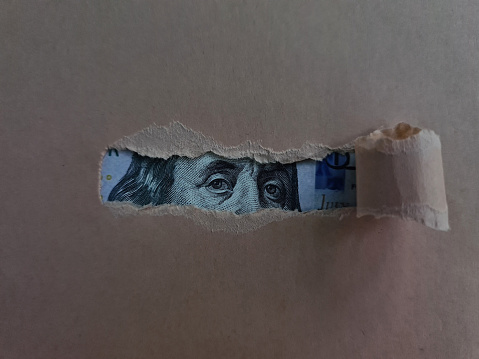 Paper torn and revealing dollar bill. Financial investment and cash income