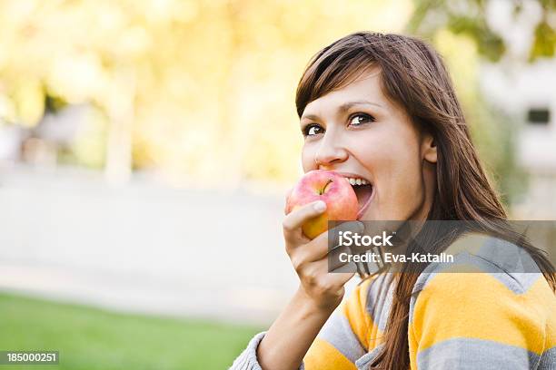 Alegre Joven Mujer Comiendo Una Manzana Foto de stock y más banco de imágenes de 20 a 29 años - 20 a 29 años, Adolescente, Adulto