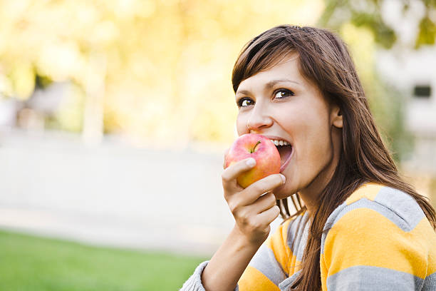istock Cheerful young woman eating an apple 185000251