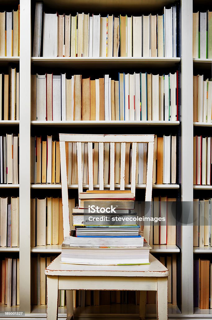 Libros en el sillón frente a la estantería de libros - Foto de stock de Abundancia libre de derechos