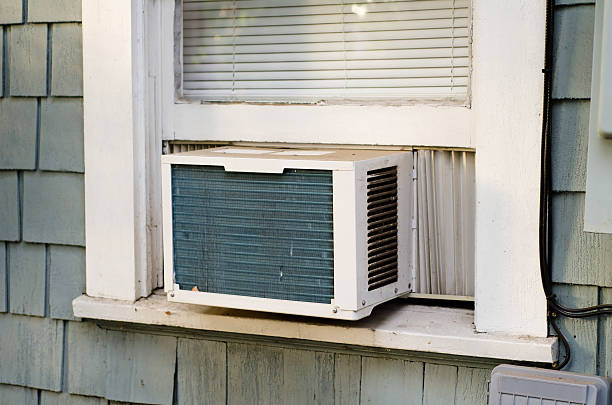 Air Conditioner An air conditioning unit sticking out a window. window ventilation stock pictures, royalty-free photos & images