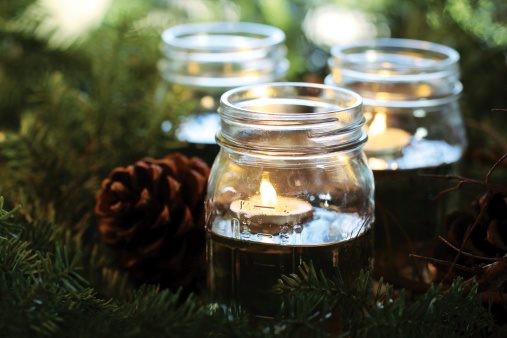 Candles float in canning jars among pine boughs and pine cones