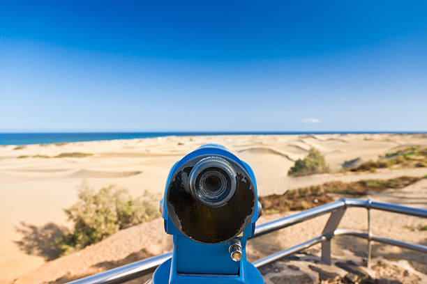 A young boy dressed in business suit and tie looks through a telescope while standing among the beach dunes in Montana de Oro State Park, California. This young entrepreneur is ready to take his new business to new heights in the afternoon sun.