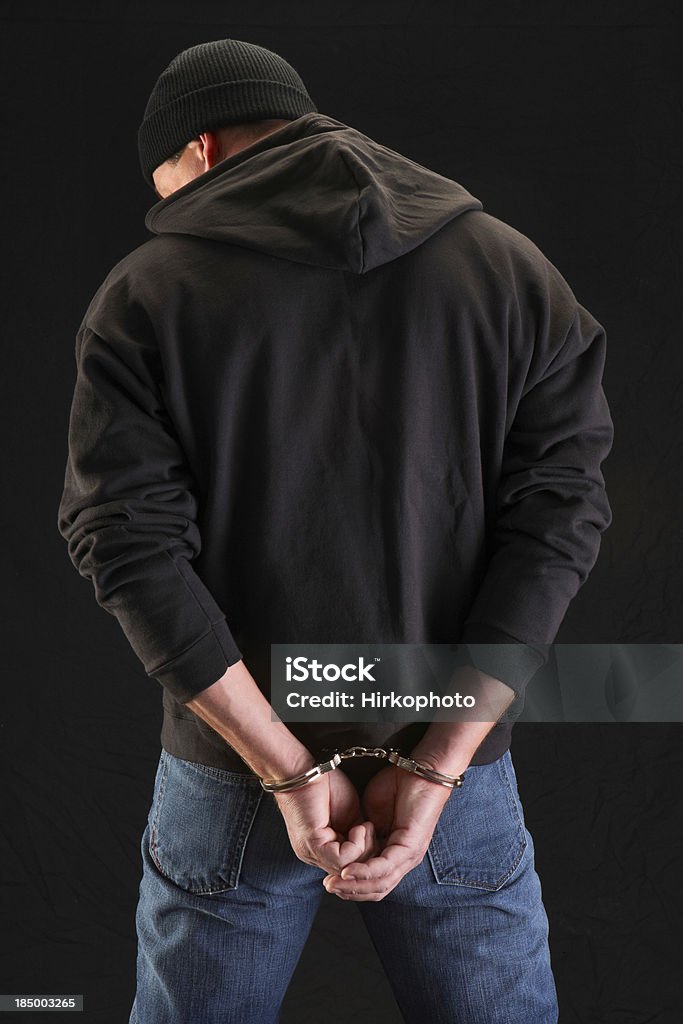 Robber on black handcuffed Man in handcuffs behind his back black sweatshirt and beanie hat. Handcuffs Stock Photo