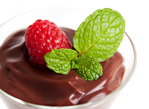 Chocolate pudding with raspberry and mint leaf garnish