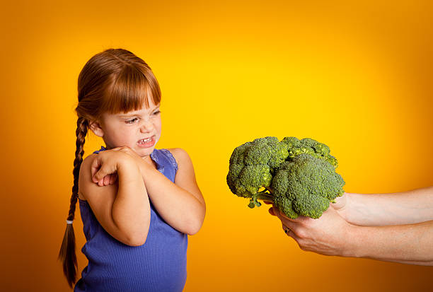 istock Young Girl Making  Face At Broccoli Being Held Towards Her 185004731